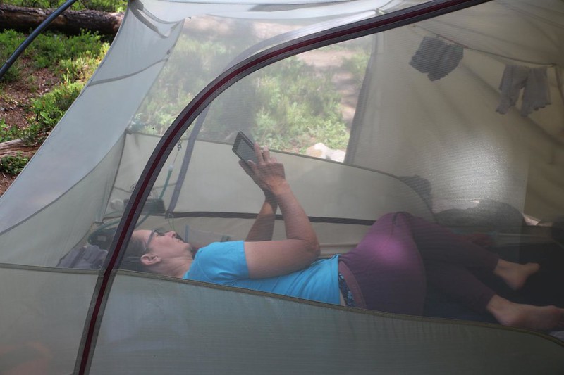 Vicki reading on her Kindle in the shady, bug-proof environment of the tent