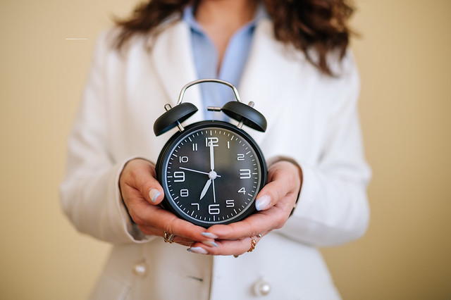 Young white-collar woman holding an analog clock in her hands