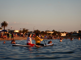 Chinese ladies on a paddleboard at sunset at Elwood Beach on a hot 39C Summer Saturday