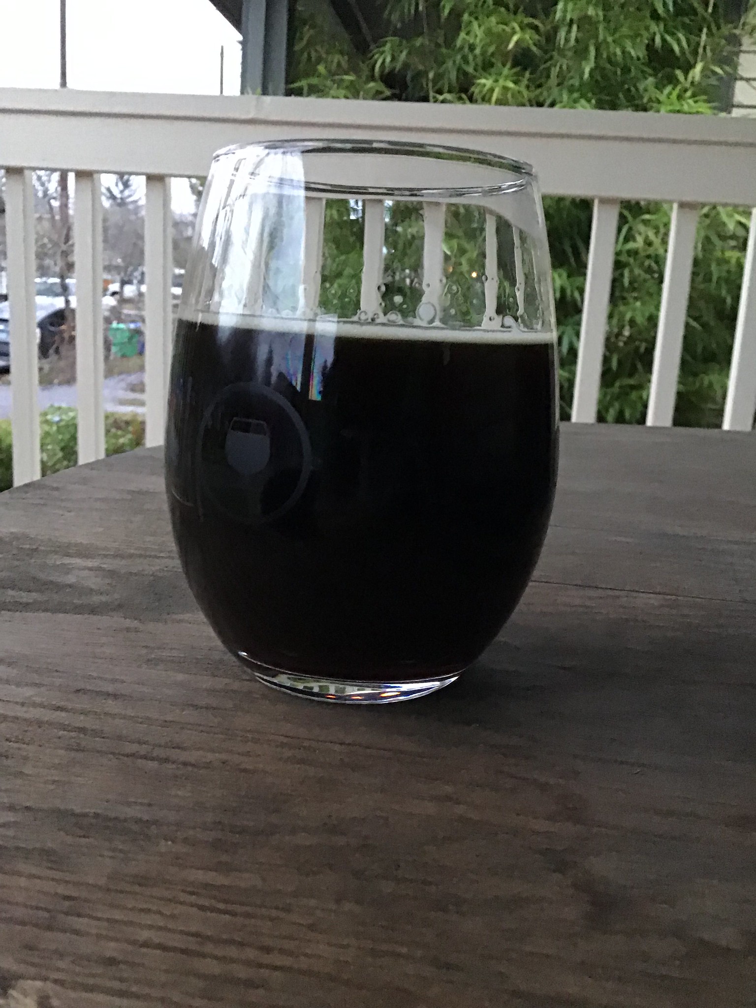 Varietal brewing's Fortress of Lies in a glass on a table outside on a cloudy day