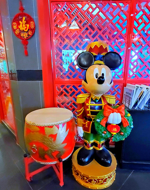 Mickey Mouse the marching band drummer, with a Christmas wreath, a snare drum and a dragon drum, with Chinese decor
