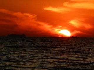 Huge red sunset, ship and boat at Elwood Beach on a warm Summer Monday