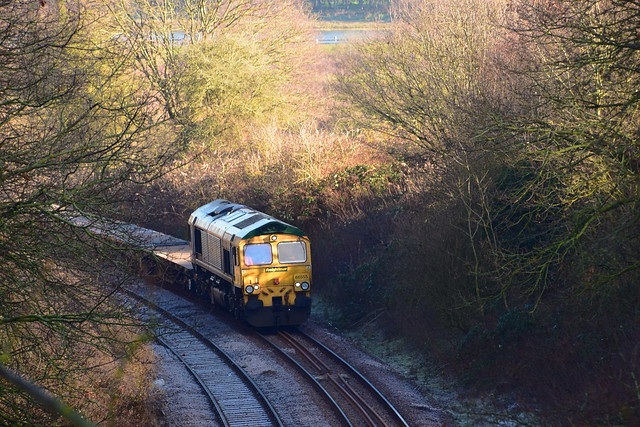 Freightliner 66555 with a rake of flat wagons, at Broomheath, Woodbridge, during track replacement works. 22 01 2023