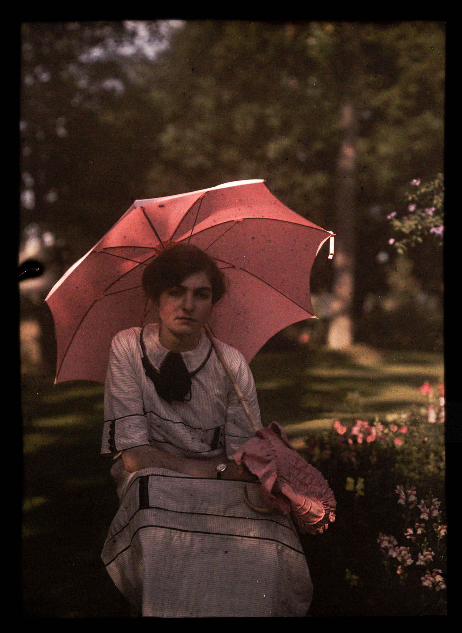 ENGLAND - SEPTEMBER 03:  An autochrome of a young girl, daughter of the photographer, sitting in the shade in a garden, holding a parasol over her shoulder, taken by Etheldreda Janet Laing. In the summer of 1908 Laing took a series of autochrome portraits of her children in the garden of the family home, Bury Knowle. 