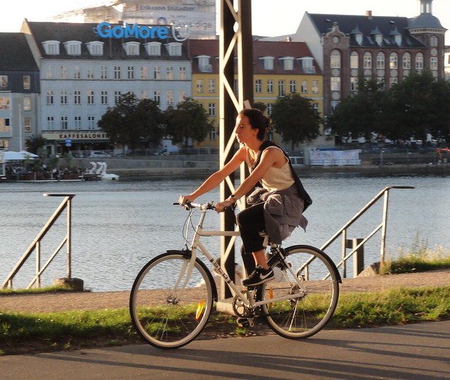 Copenhagen girl  on a bike cruises lakeside before sunset
