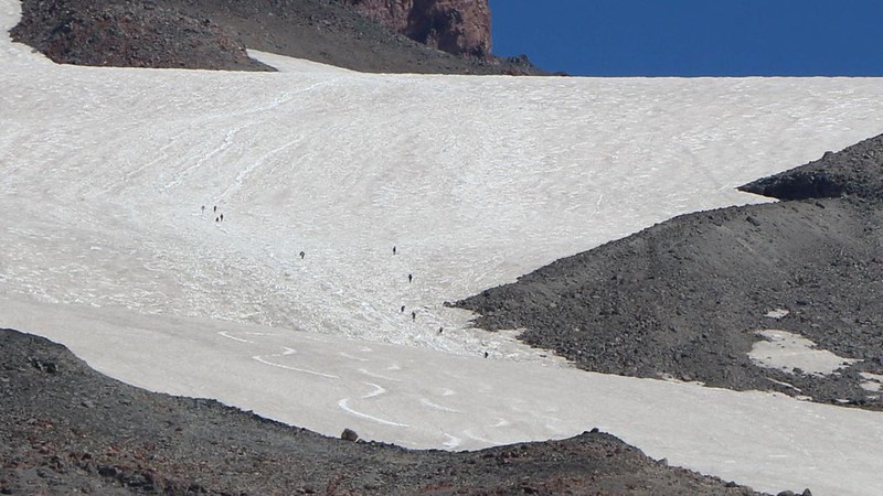 Zoomed-in view of mountaineers climbing up the Muir Snowfield on Mount Rainier, following the Camp Muir Route