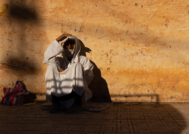 Algerian man in bournous sit in the sun in the street, North Africa, Ghardaia, Algeria
