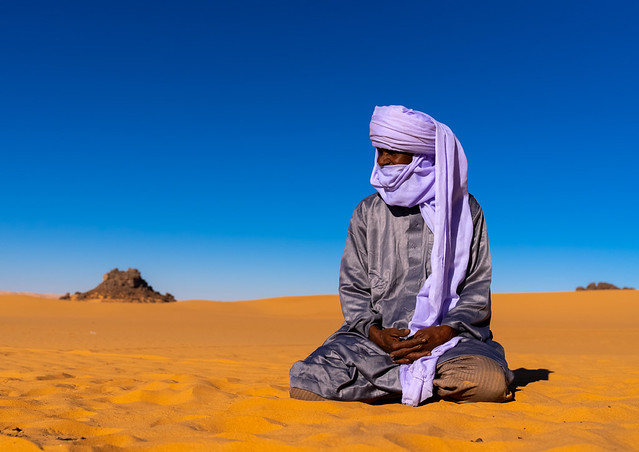 Tuareg sit in the Sahara desert, North Africa, Erg Admer, Algeria