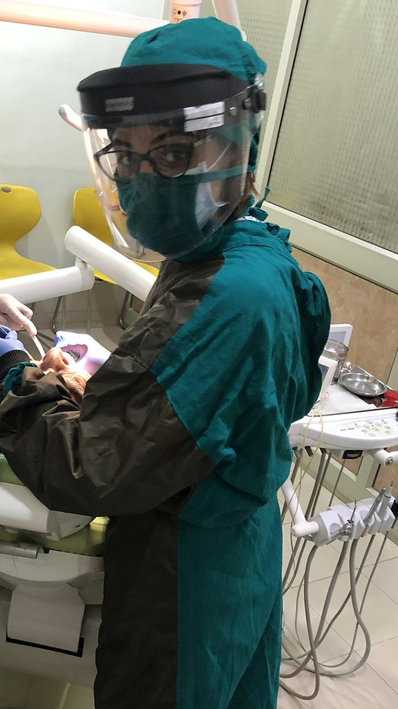 A woman wearing a full set of dental scrubs and a protective face guard.