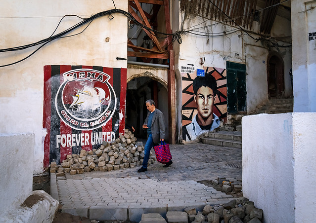 Man passing near murals of football and revolution in the casbash, North Africa, Algiers, Algeria