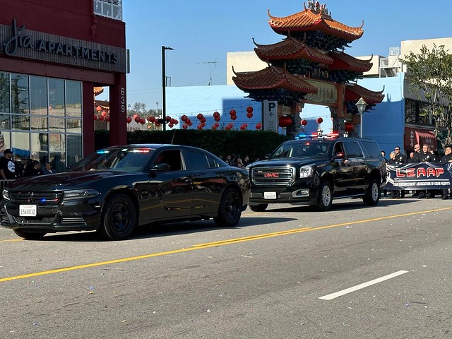 Los Angeles Police Department Chief of Police Michael Moore riding on an open top convertible cars and unmarked patrol cruisers, Law Enforcement Association of Asian Pacifics have crossed at North Broadway and Ord Street intersection traffic signal