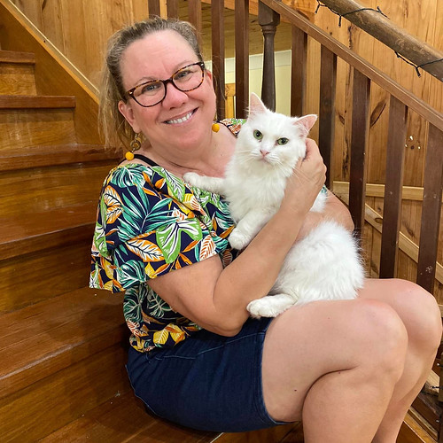 middle aged woman wearing glasses and holding a white fluffy cat