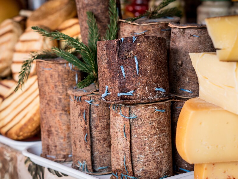A close-up of the burduf cheese in the market, enclosed in fir bark, having a cylindrical shape