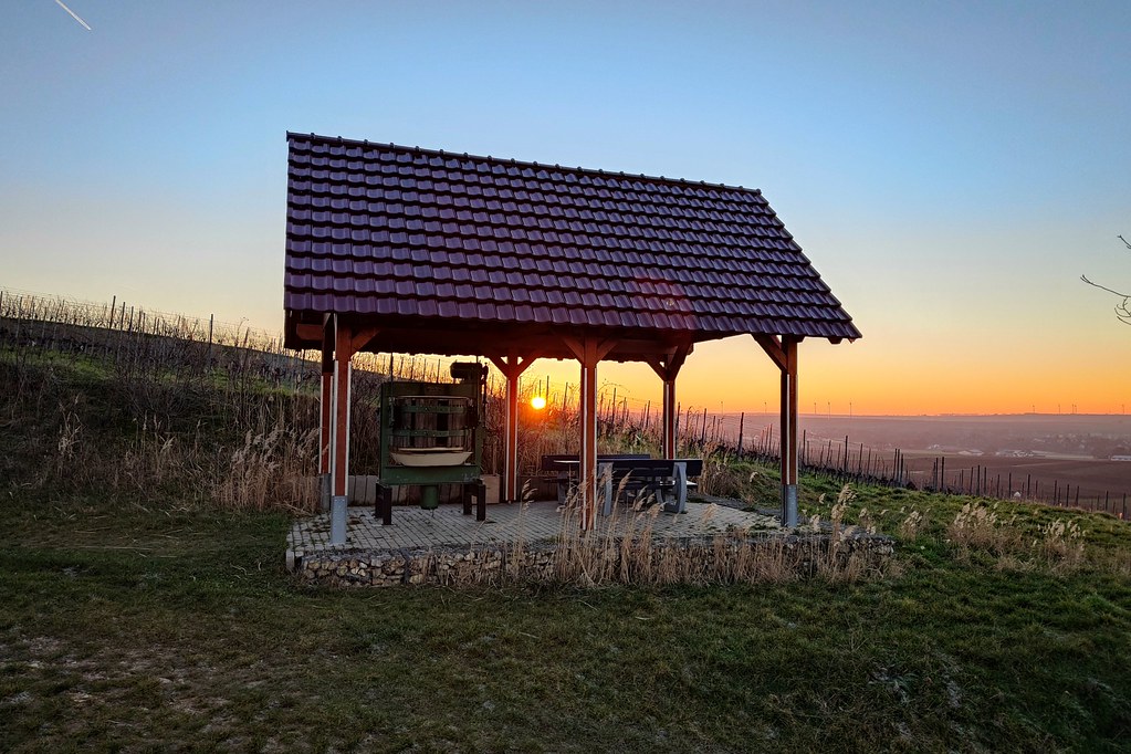 Schutzhütte mit Kelter und Tisch - aufgehende Sonne dahinter am Horizont