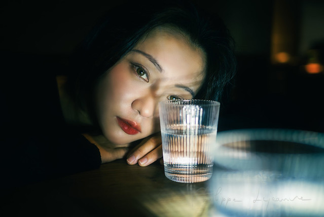 Young woman looking through a glass of water