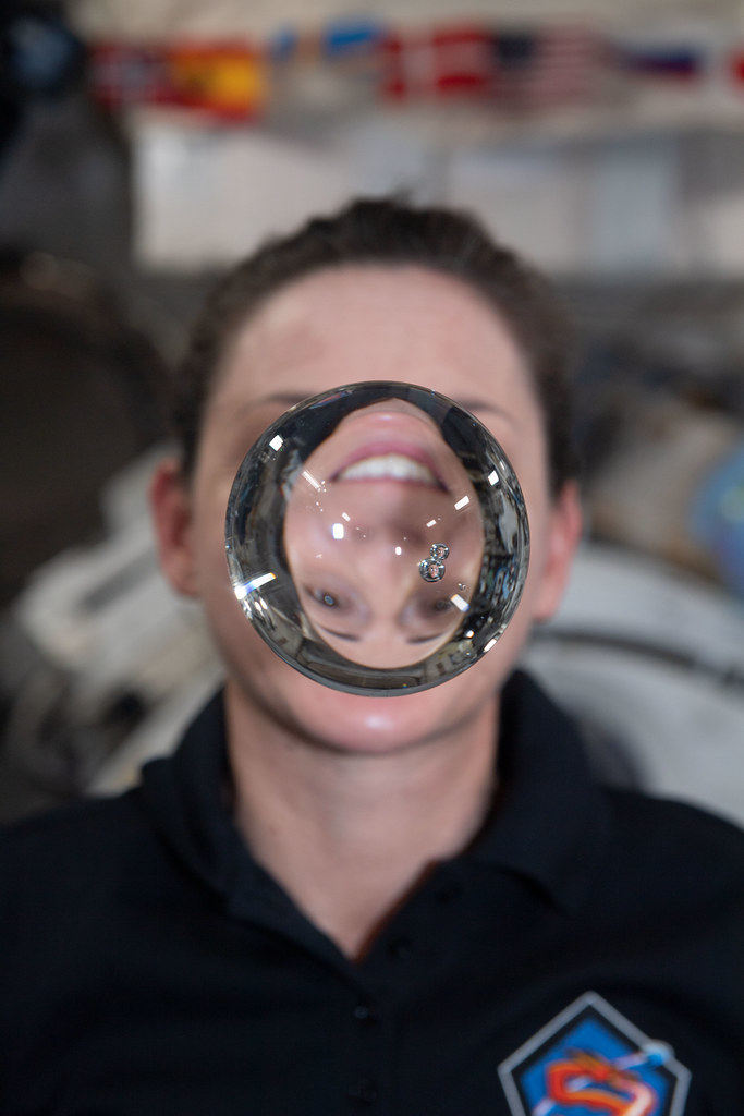 Astronaut Nicole Mann's image refracts through a sphere of water