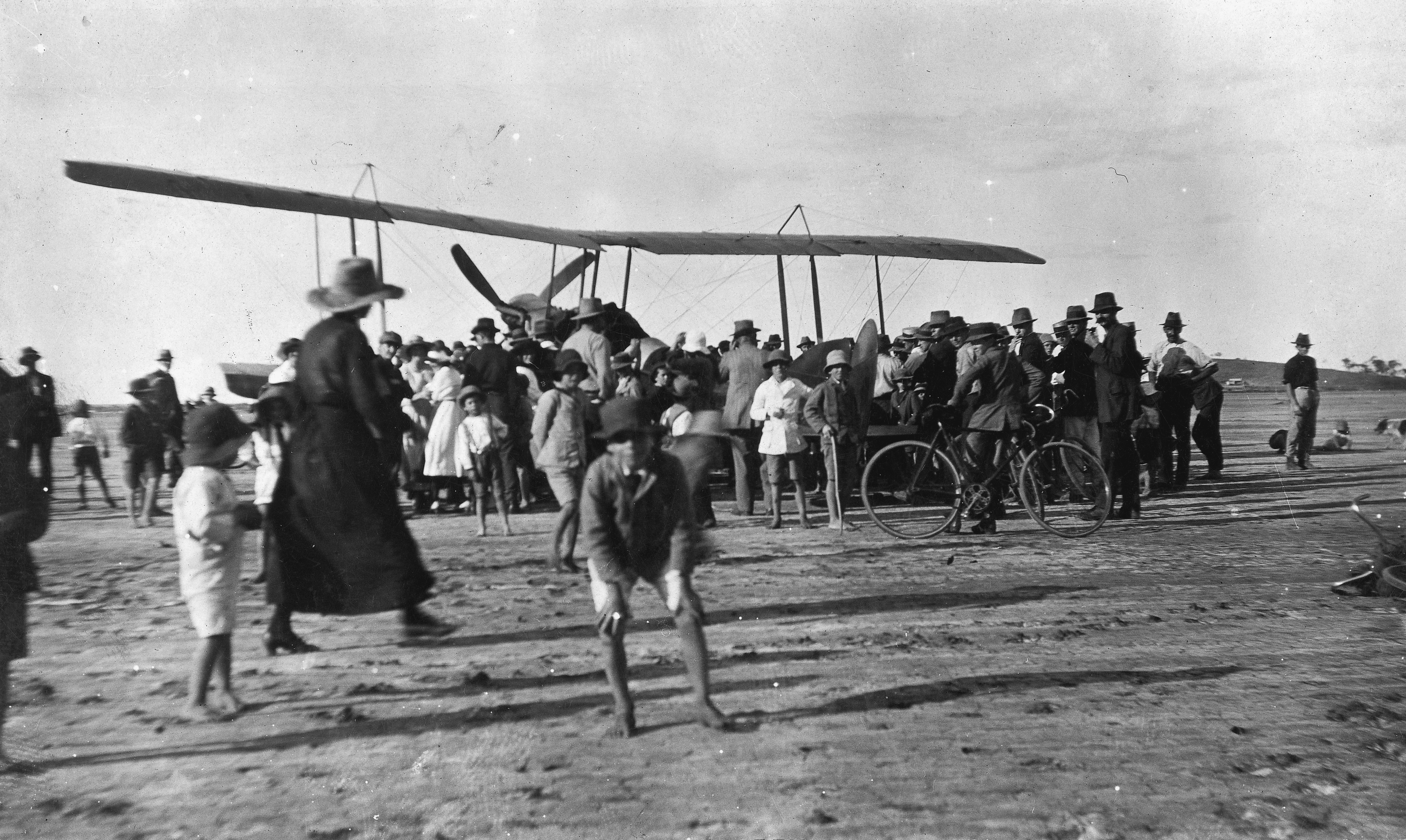 Crowd gathers around an aeroplane that landed at Meat Works Flat, Parsons Point, Gladstone, ca. 1920