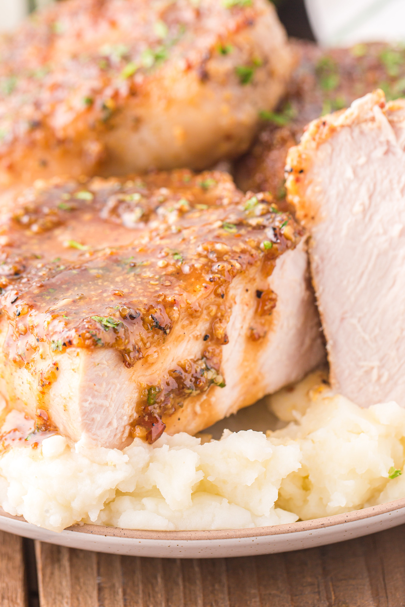 Pork chop with honey mustard sauce cut to show the perfectly cooked inside of the pork. Served over mashed potatoes. 