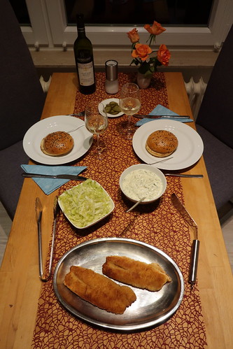 Do-it-yourself Fischburger mit panierten Rotbarschfilets, Remoulade, Eisbergsalat, Gurkensalat und frisch gebackenen Buns (Tischbild)