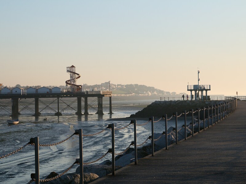 The pier in Herne Bay at sunset. The light is warm. You can see the amusement park on the pier.