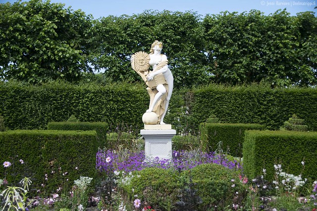 Naista esittävä patsas kukkien keskellä