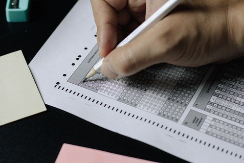 a person fills in a question on a scantron with a white pencil