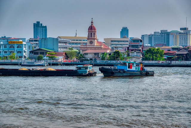 Barges passing Santa Cruz church on the Chao Phraya River in Bangkok, Thailand