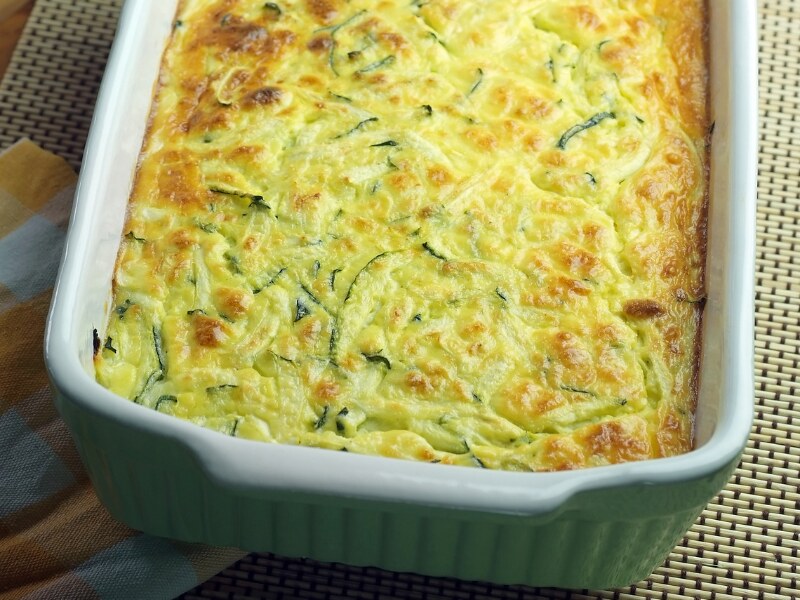 A large white baking tray with the souffle in it. It has a yellow crust on top, and you can see pieces of grated courgette through it.