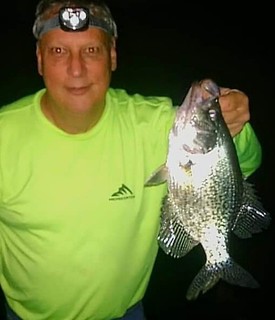 Photo taken at night of man holding a fish