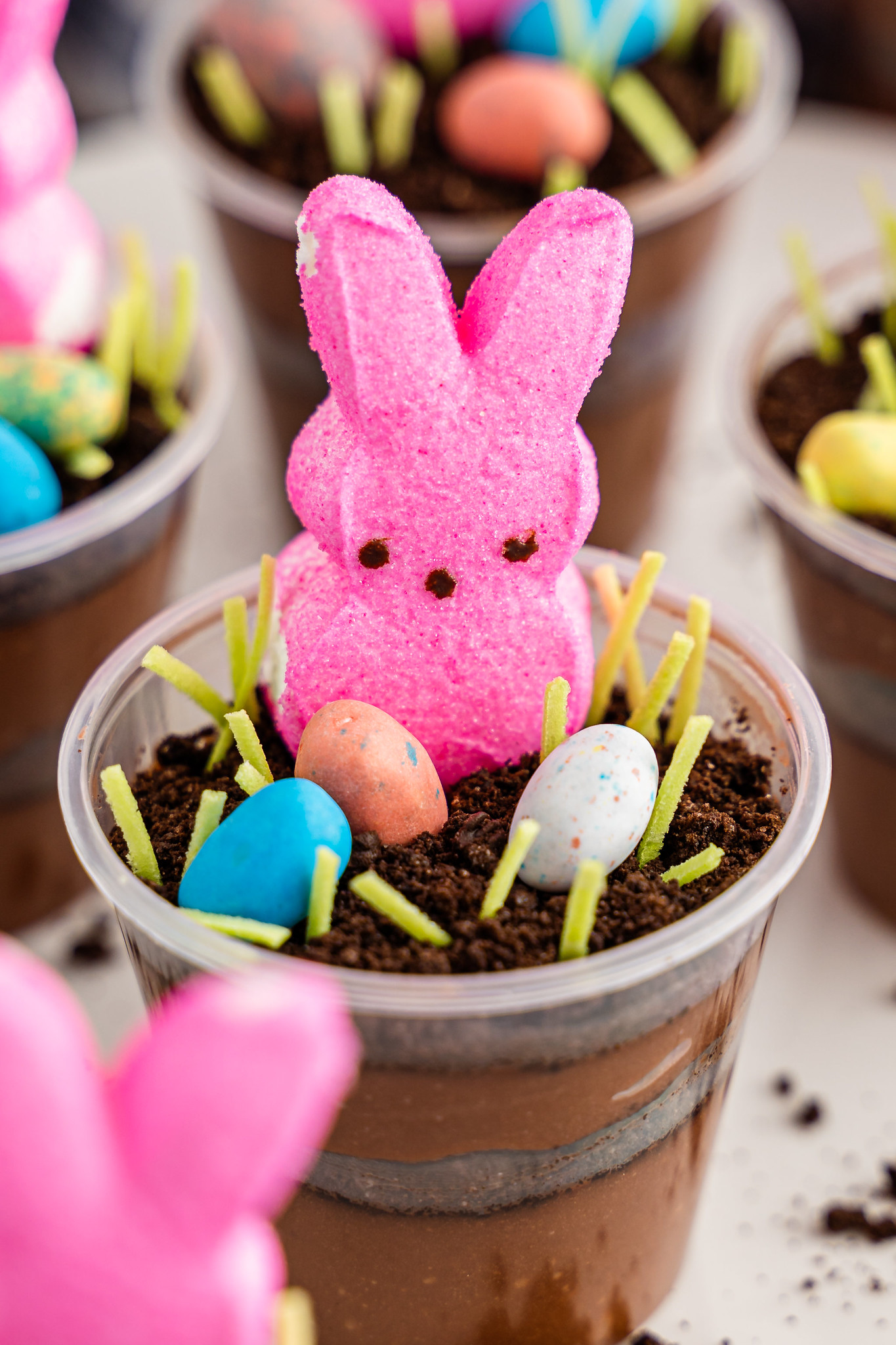 Close up shot of pink peeps bunny on top of crushed oreos with chocolate eggs and edible easter grass around it