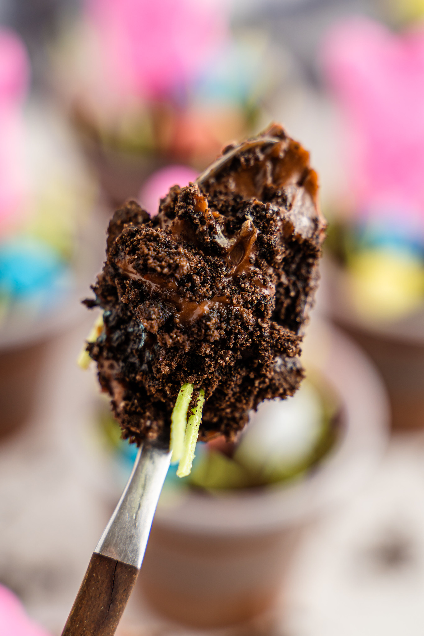 A spoonful of chocolate pudding and crushed oreos with edible easter grass sticking out