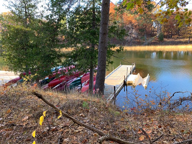 Oak trees and red canoes at a wooden dock with a canoe and kayak launch on the Old Ausable Channel in the Pinery Provincial Park on Lake Huron and near the town of Grand Bend , Martin’s photographs , Ontario , Canada , October 27. 2022