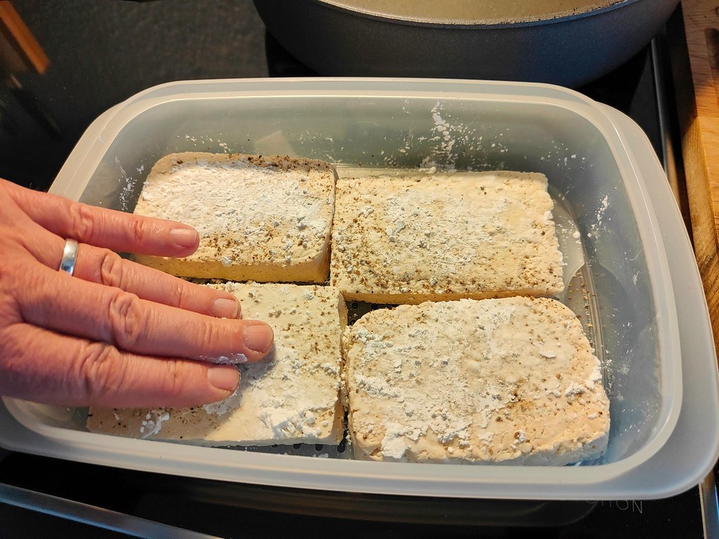 Tofu scheiben pfeffern, mit Speisestärke bestreuen und verteilen