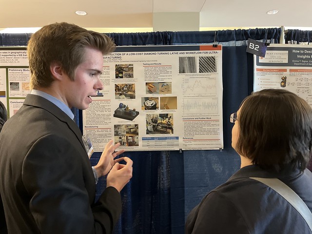Cyrus Lloyd discusses his research project with a symposium visitor