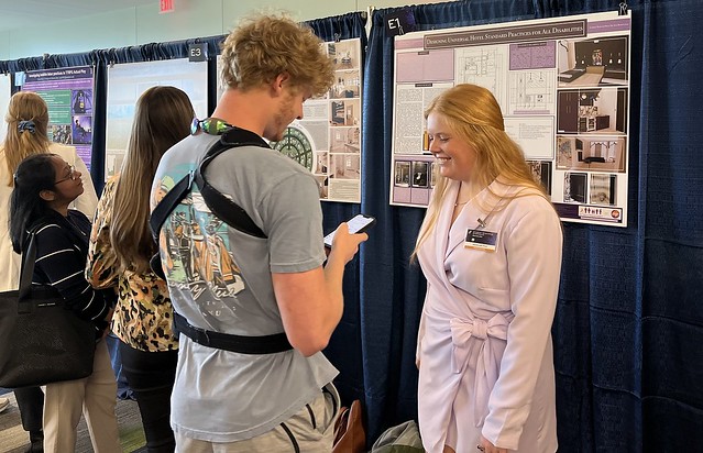 Madeline Pick speaks with a symposium visitor about her research project