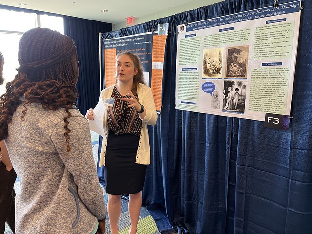 Zana Christjohn presents her research project to a symposium visitor