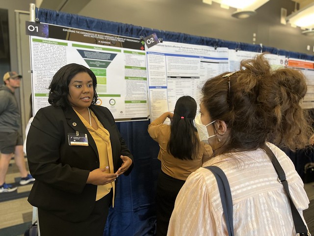 Makeda Nurradin talks with a symposium visitor about her research project