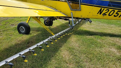 A close-up of the spray boom under a crop duster.