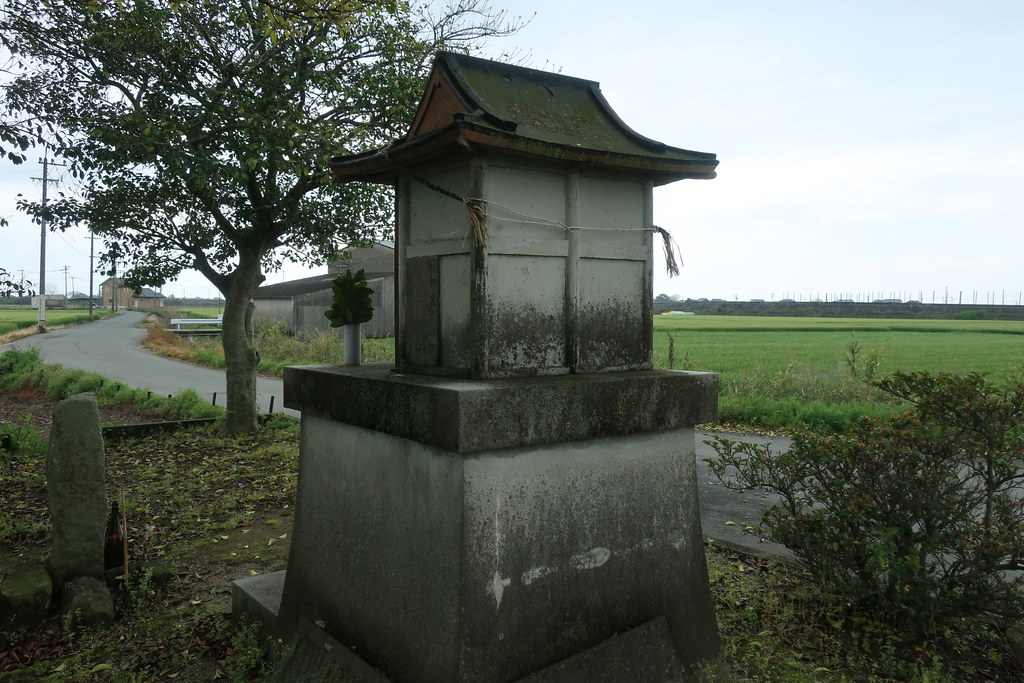 Shrine surrounded by croplands with the sea in the distance