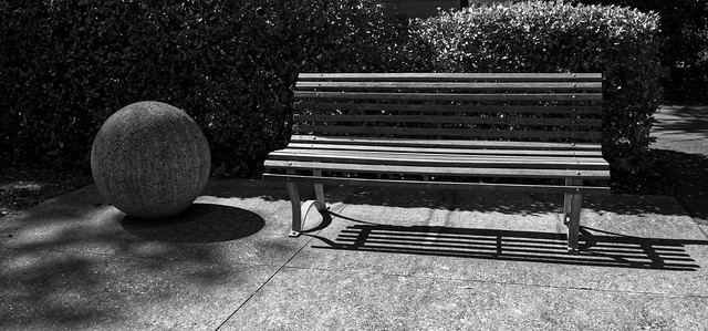Concrete sphere and wooden bench. *
