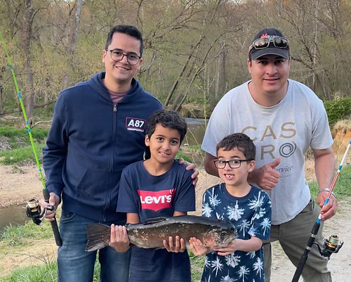Photo of two adult men and two boys holding a rainbow trout