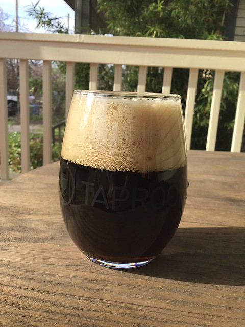 Steeplejack tropical stout with excessive head in glass on a table outside