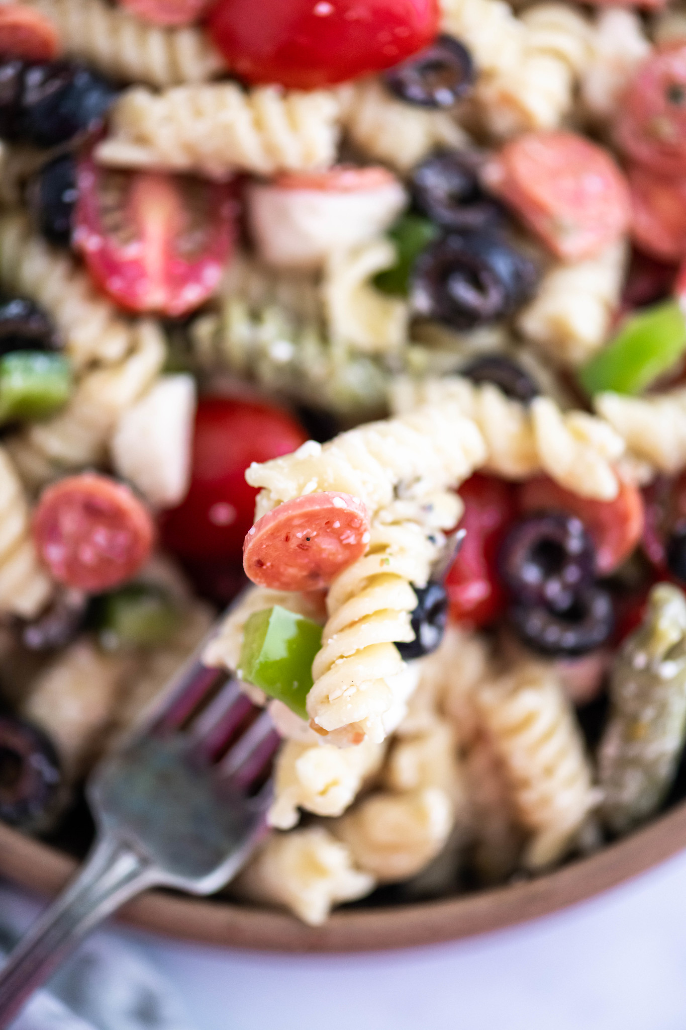 Close up photo of fork piled with pizza pasta salad.