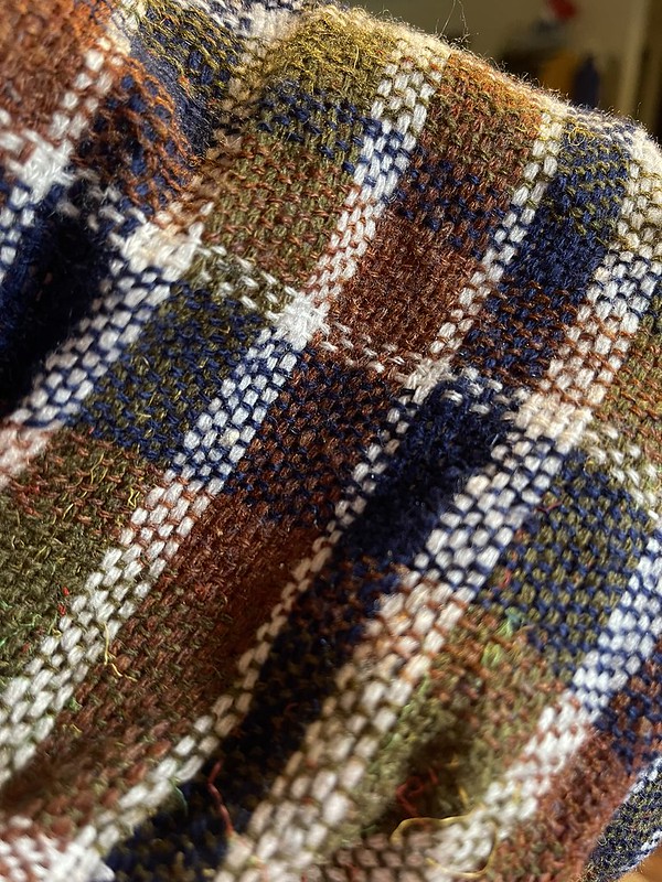 Close up of olive, dark red, blue, and white plaid fabric. The white looks prominently stripey