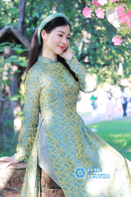 A charming, beautiful beauty queen runner-up is posing gracefully in an Ao Dai blue floral traditional Vietnamese dress and a Vietnamese turban.