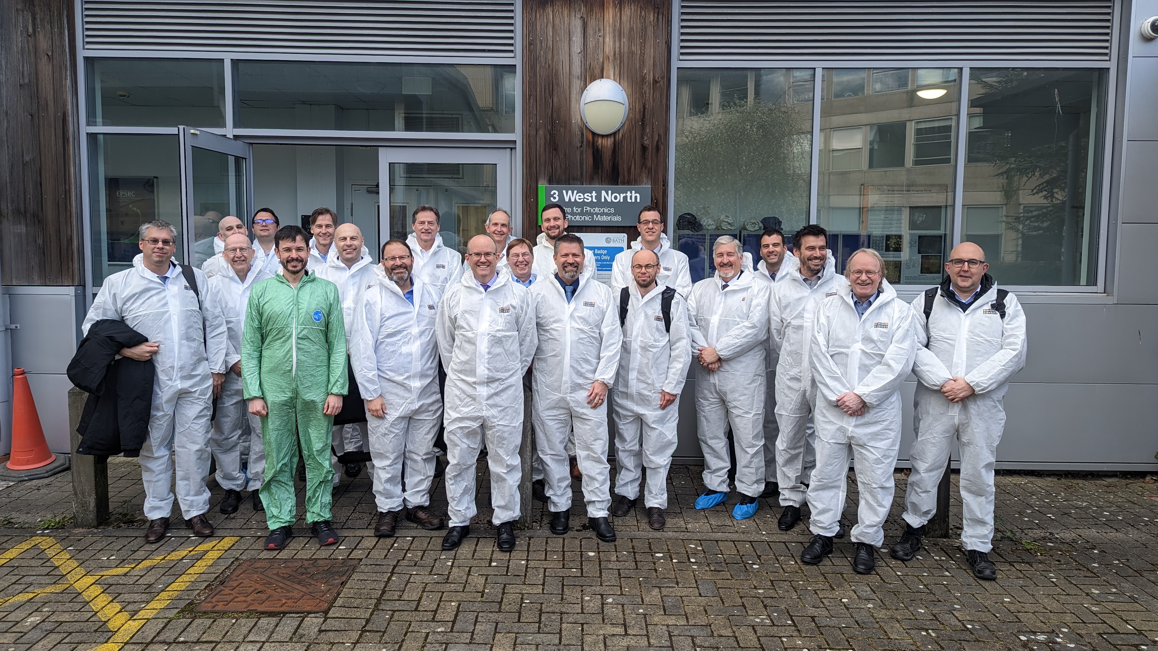 A group of mean wearing protective suits stands outside the Centre for Photonics and Photonic Materials