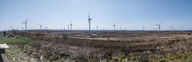 A panoramic photo of a moorland wind farm showing multiple wind turbines.