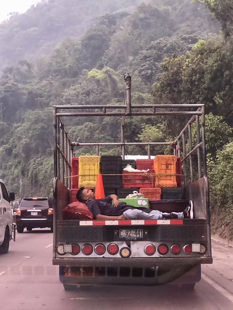 Worker snoozing in the back of a truck, highway near Los Chorros, El Salvador