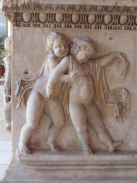 Naughty Cupids (Erotes) 150-160 AD, sculptured detail of Attic Sarcophagus with wreathed chubby Erotes holding a bunch of grapes, young and wingless ones who stagger drunkenly home from a symposium. Athens, National Archaeological museum