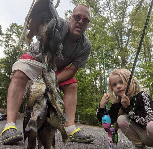 Photo of man and young daughter holding a large group of fish on a line